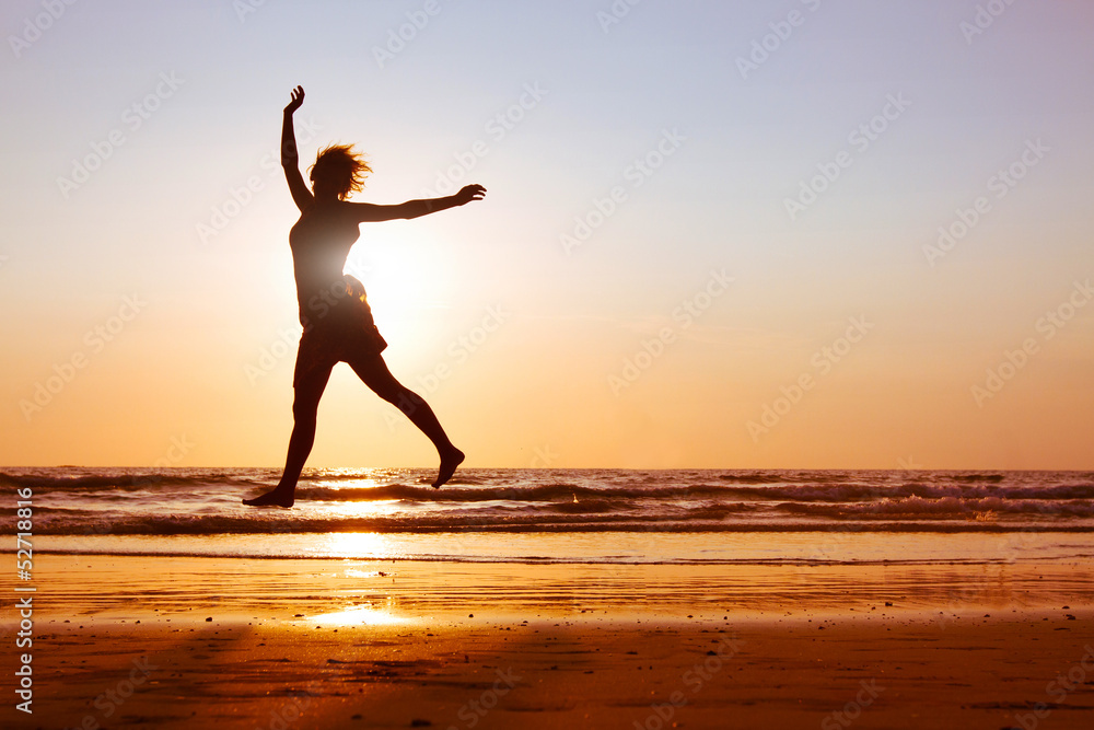 happy woman dancing on the beach at sunset, silhouette