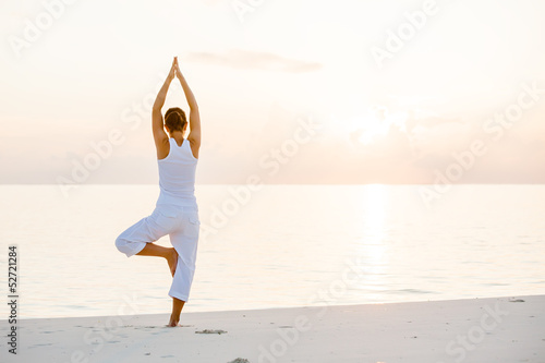 Fototapeta Caucasian woman practicing yoga at seashore