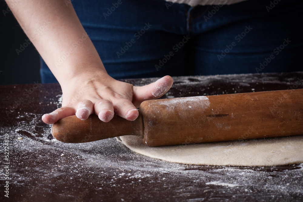 Hand on a rolling pin preparing pizza dough Hand on a rolling pin preparing pizza dough