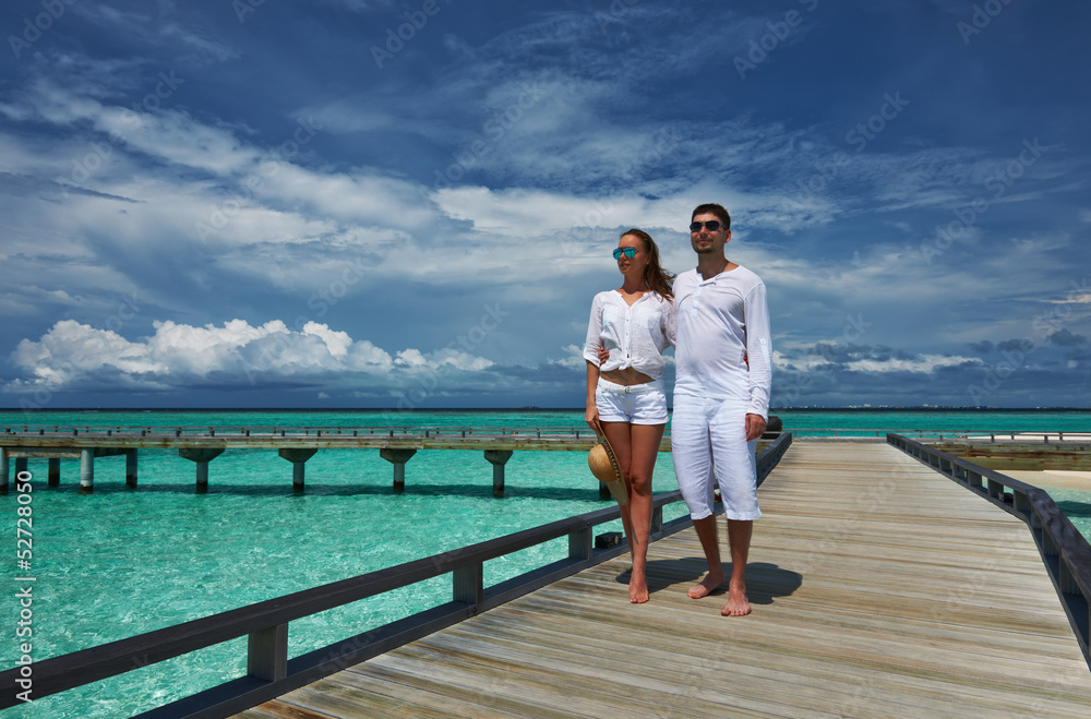 Couple on a beach jetty at Maldives Couple on a beach jetty at Maldives
