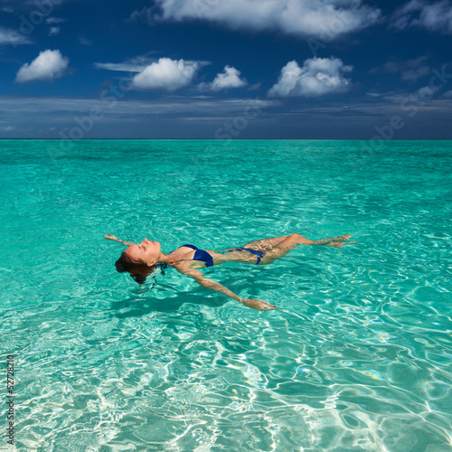 Woman in bikini lying on water