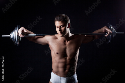 Portrait of attractive guy posing with barbell
