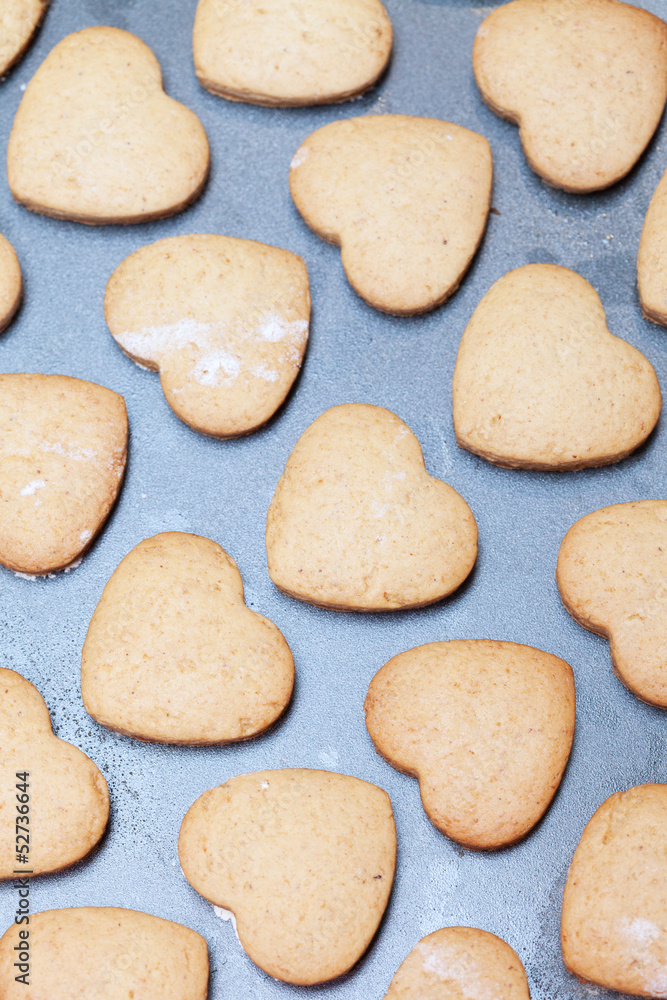 Rows of heart shaped biscuits on metal baking tray