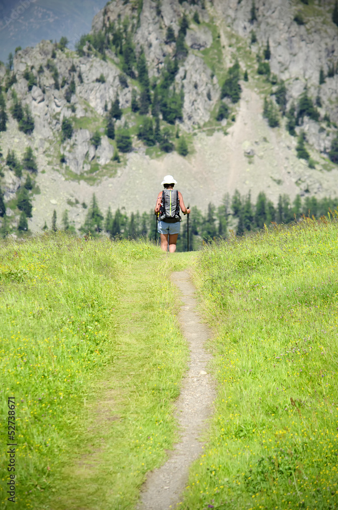 Girl with backpack walking, trekking up a mountain