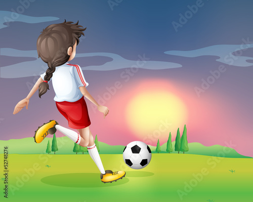 A girl playing football in the afternoon
