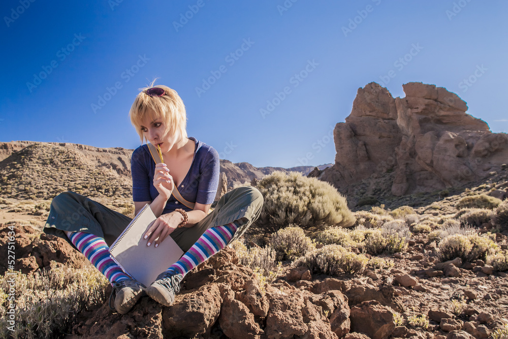 Girl is sitting on the rock and thinking with notebook