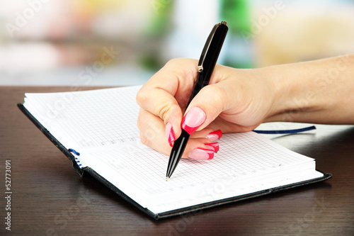 Hand signing in notebook, on bright background