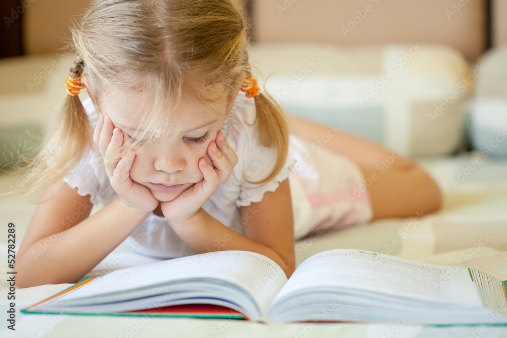 little girl lying on the bed and reading a book little girl lying on the bed and reading a book