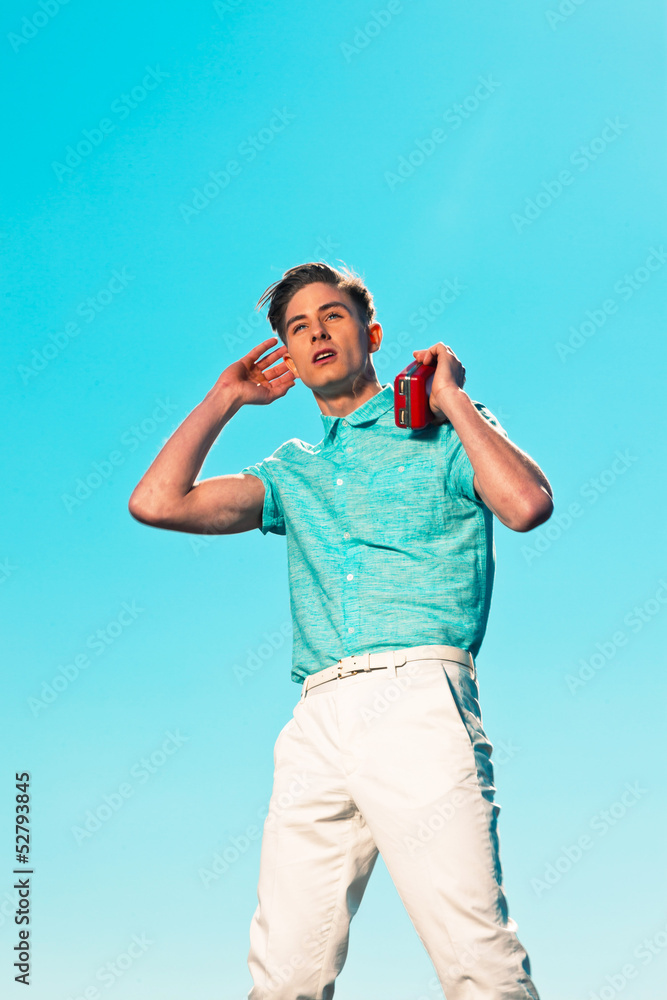 Retro fifties summer fashion man in blue shirt listens to portab Retro fifties summer fashion man in blue shirt listens to portab