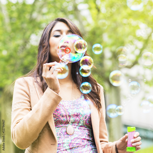 Beautiful young woman blowing bubbles.