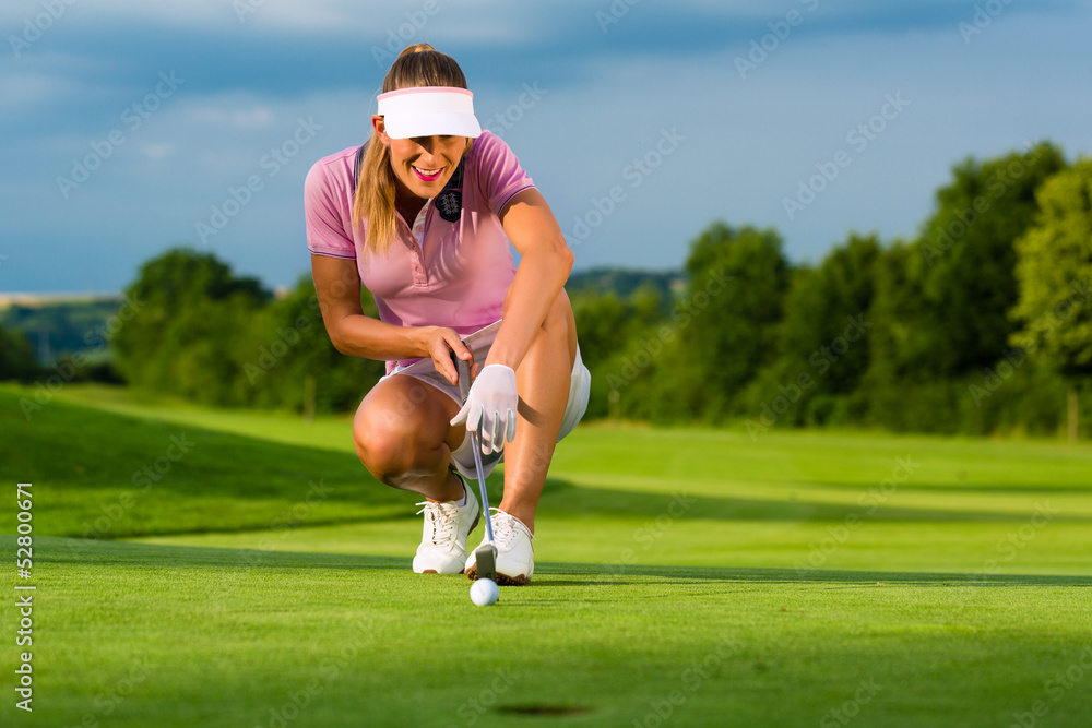 Young female golf player on course aiming for her put Young female golf player on course aiming for her put