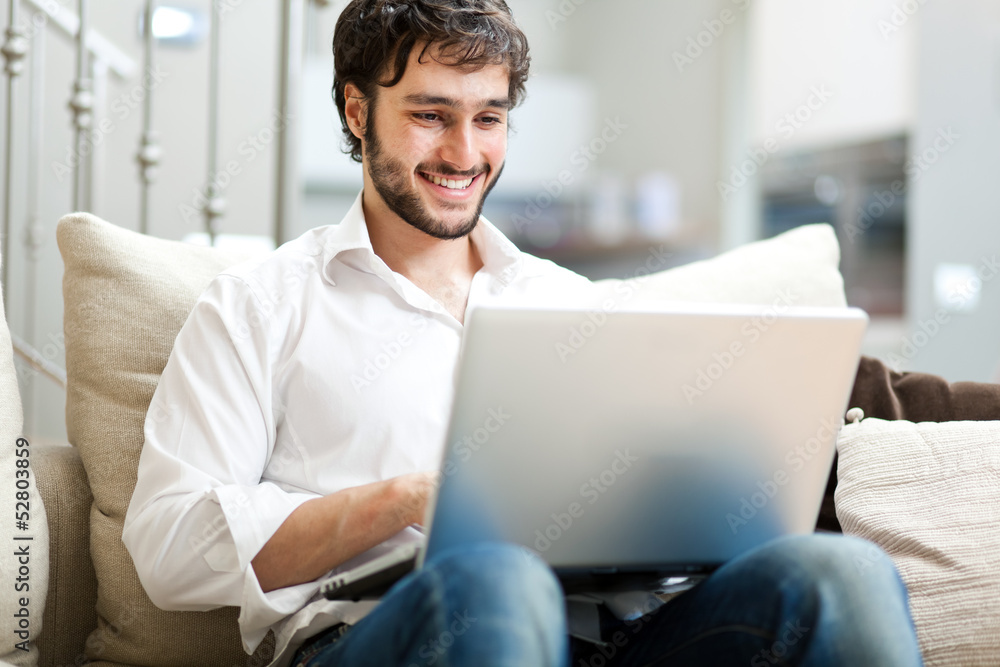 Young man relaxing on the sofa with a laptop Young man relaxing on the sofa with a laptop