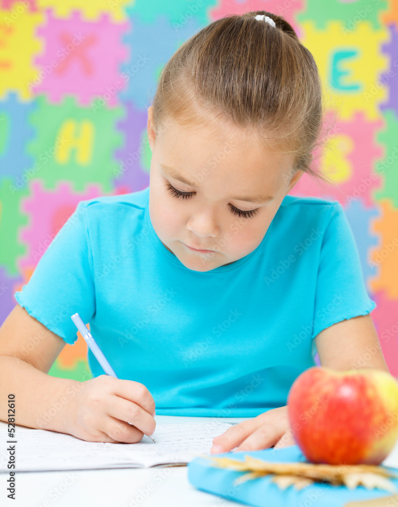 Little girl is writing using a pen Little girl is writing using a pen