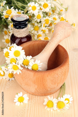 Fototapeta Naklejka Na Ścianę i Meble -  Essential oil and chamomile flowers in mortar on wooden table
