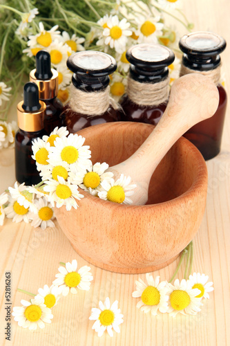 Fototapeta Naklejka Na Ścianę i Meble -  Essential oil and chamomile flowers in mortar on wooden table