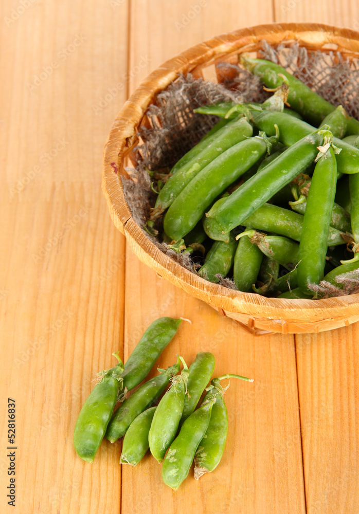 Green peas in basket on wooden table Green peas in basket on wooden table