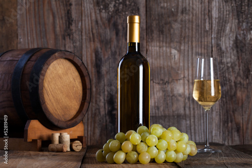 White wine, grapes, old bottle and a barrel.