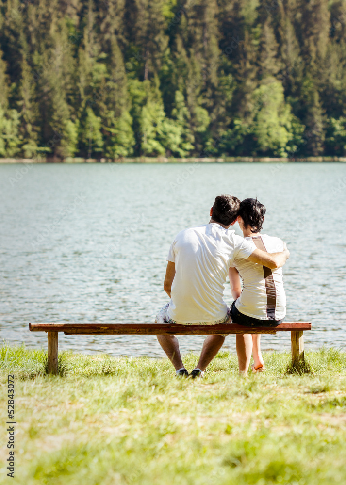 Fototapeta premium Young lovers sitting on wooden bench