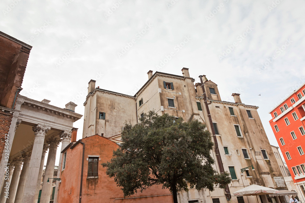 Old buildings with tree and cloudy sky in Venice. Italy.