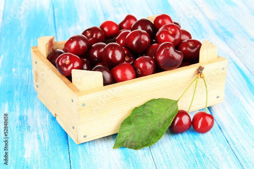 Cherry berries in wooden box on wooden table close-up