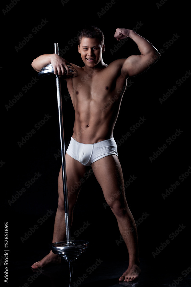 Smiling strong man posing with barbell in studio Smiling strong man posing with barbell in studio