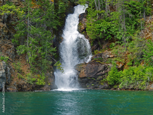 Beautiful Mountain Waterfall Flowing into a Green Lake