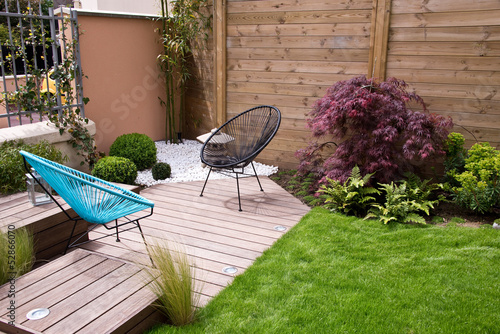 Terrasse et et petit jardin moderne, coin zen avec du gravier blanc et un érable japonais, fauteuils et pelouse, palissade en bois photo