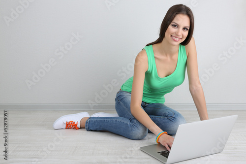 Beautiful young woman sitting with laptop in room