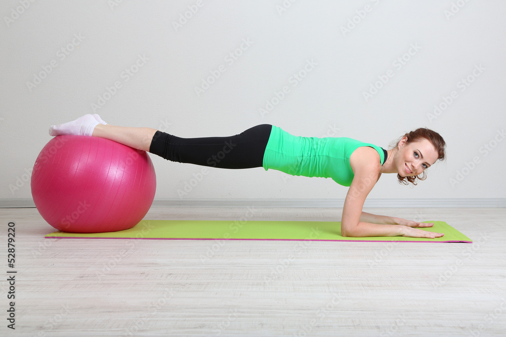 Naklejka premium Portrait of beautiful young woman exercises with gym ball