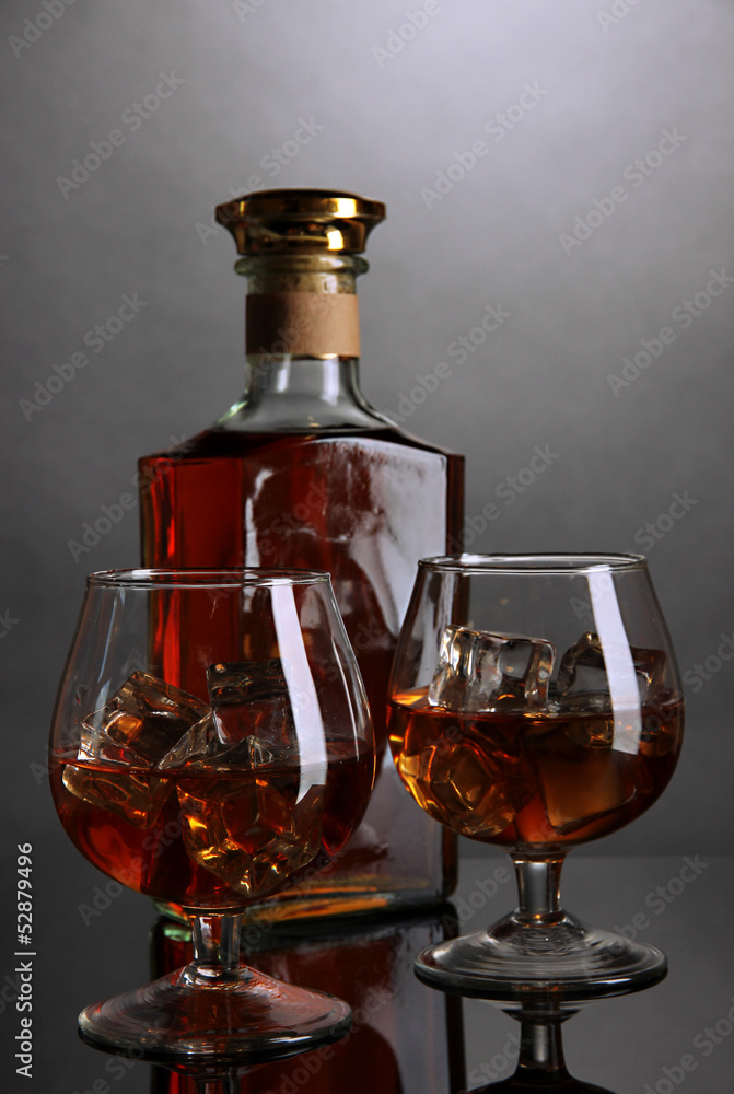 Brandy glass with ice and bottle on grey background Brandy glass with ice and bottle on grey background