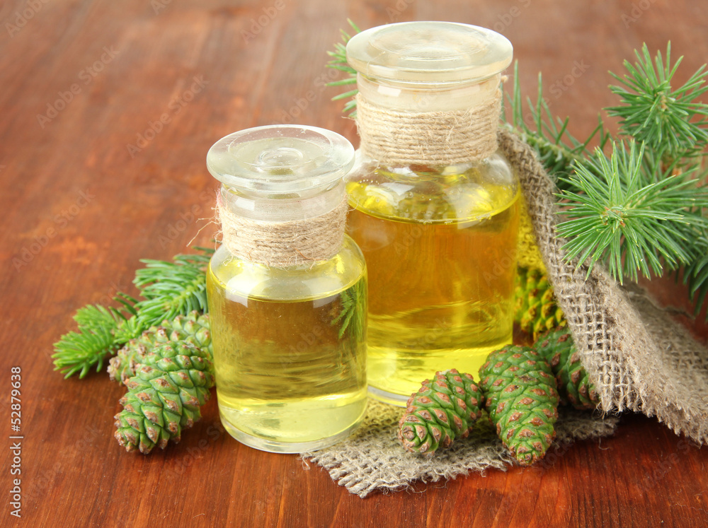 Bottles of fir tree oil and green cones on wooden background Bottles of fir tree oil and green cones on wooden background