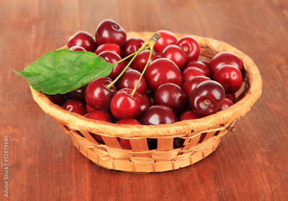 Cherry berries in wicker basket on wooden table close-up Cherry berries in wicker basket on wooden table close-up