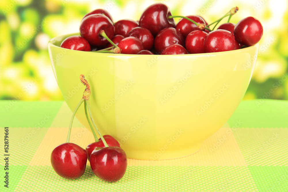 Cherry berries in bowl on table on bright background Cherry berries in bowl on table on bright background