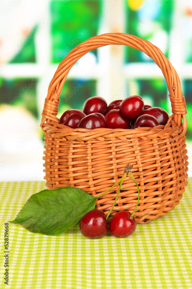 Cherry berries in wicker basket on table in room Cherry berries in wicker basket on table in room