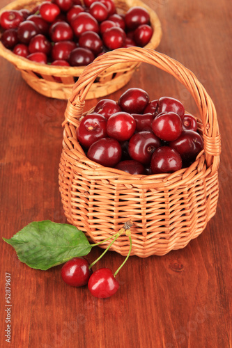 Cherry berries in wicker baskets on wooden table close-up