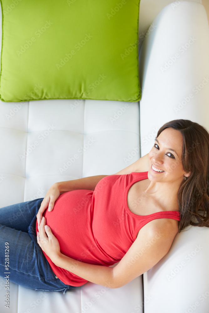 Overhead View Of Pregnant Woman Relaxing On Sofa Overhead View Of Pregnant Woman Relaxing On Sofa