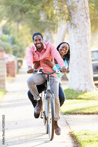 Couple Cycling Along Suburban Street Together