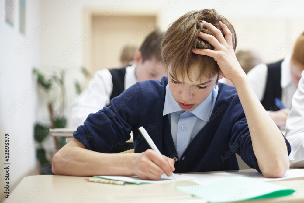 school boy struggling to finish test in class. school boy struggling to finish test in class.