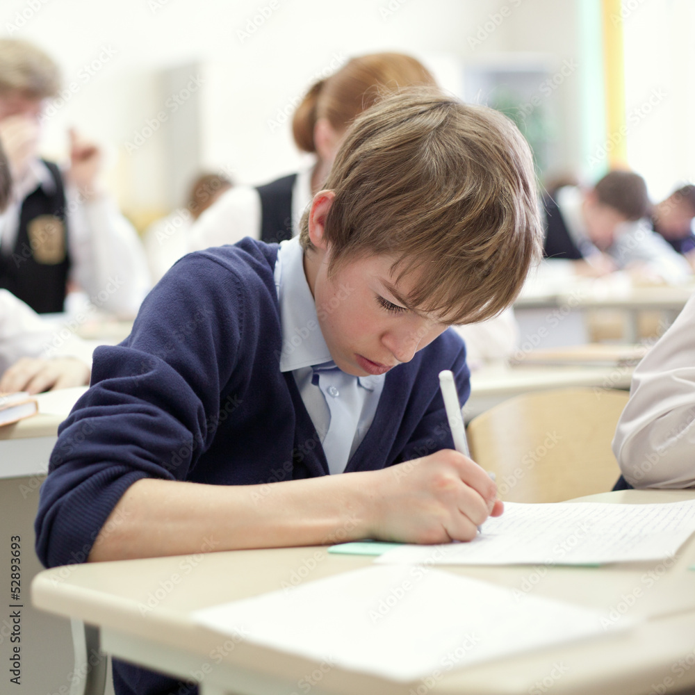 school boy struggling to finish test in class. school boy struggling to finish test in class.