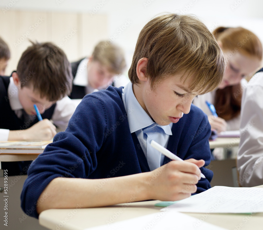 school boy struggling to finish test in class. school boy struggling to finish test in class.