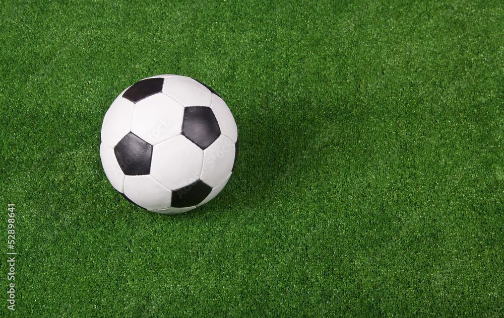 Black and white football or soccer ball, green gridiron Black and white football or soccer ball, green gridiron