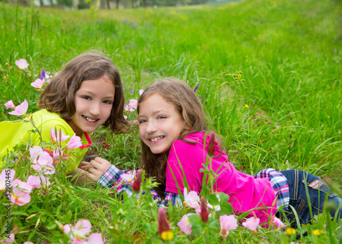 happy twin sister girls playing on spring flowers meadow