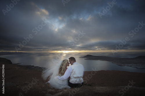 Newlyweds observing sunset in Canary Islands.