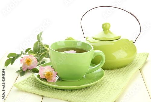 Cup and teapot of herbal tea with hip rose flowers