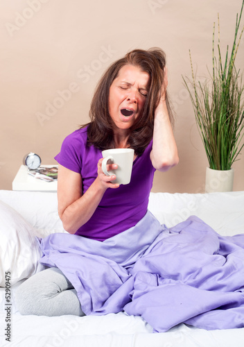 Gähnende Frau mit Kaffetasse in der Hand