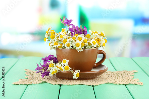 Bouquet of chamomile flowers in cup  on bright background