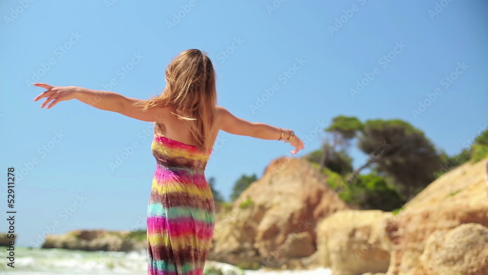 Happy excited young woman turning round by the sea Happy excited young woman turning round by the sea