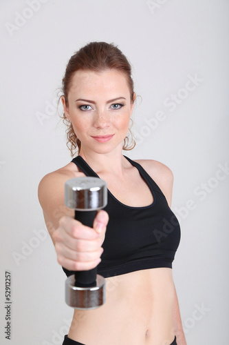 Beautiful young woman exercises with dumbbell