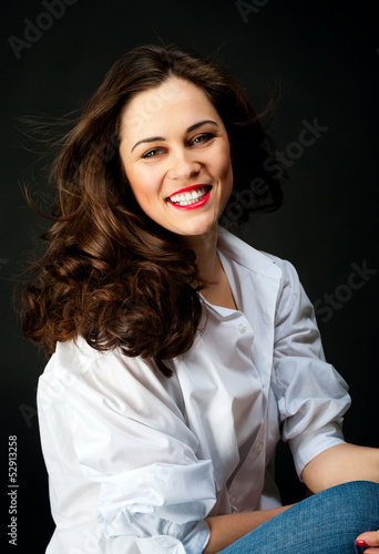 Portrait of smiling young woman with long hair in jeans and whit