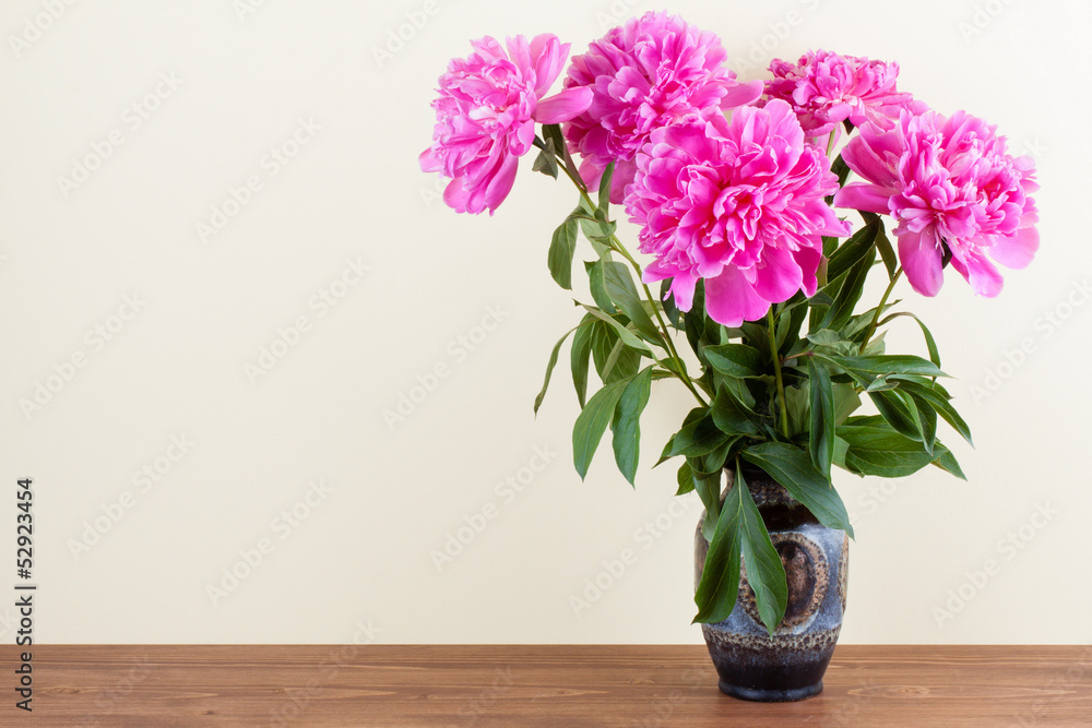 Peony flowers bouquet in vintage vase on wooden table